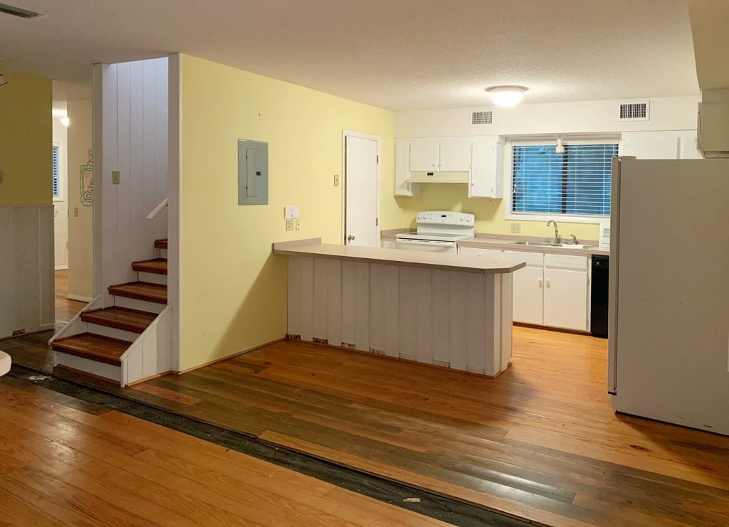 Before photo of kitchen with yellow walls and hole in floor