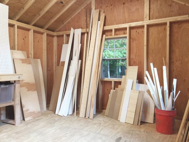 unorganized scrap wood leaned up against walls of unfinished shed